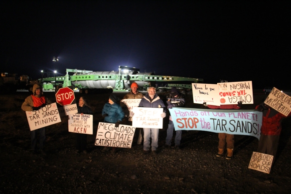 Protesters demonstrating against a megaload bound for a tar sands mining site in Canada gather in front of it at the Port of Umatilla on Sunday evening. The 300-foot-long, 20-foot-high transport scheduled to travel through Hermiston on Monday night has been rescheduled to leave on Sunday, December 1 (Hermiston Herald/Colin Murphey photo).
